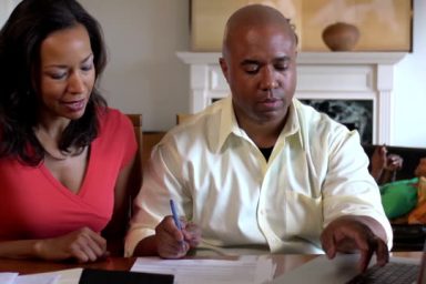 Medium shot of husband and wife discussing important documents.